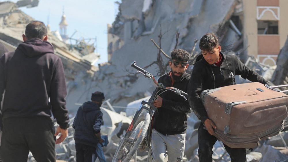 Palestinians walk through rubble in Khan Younis (file photo)