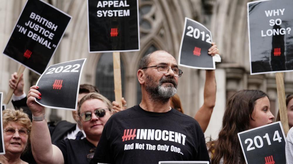 Andy Malkinson in a black T-shirt reading "Innocent" outside the Royal Courts following his appeal