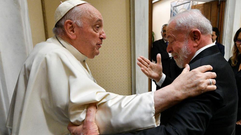 Pope Francis and Brazil's President Luiz Inácio Lula da Silva greet each other, holding one another's elbow and shoulder, while talking, at the Vatican