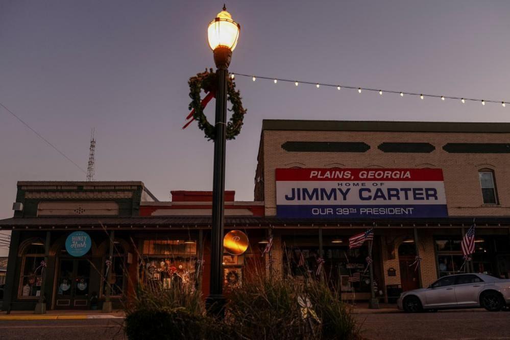 A sign that reads "Plans, Georgia Home of Jimmy Carter Our 39th President" hangs outside a shop