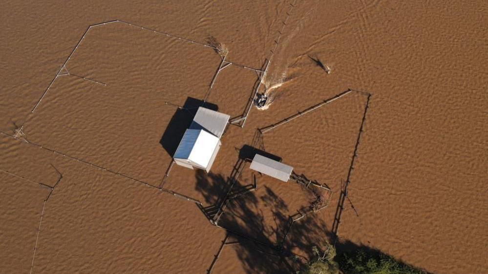 a home stranded amid brown floodwater seen from above