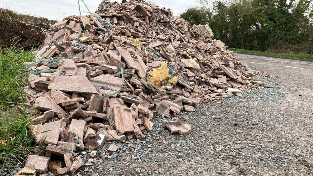 Large pile of roofing tile rubble next to a road