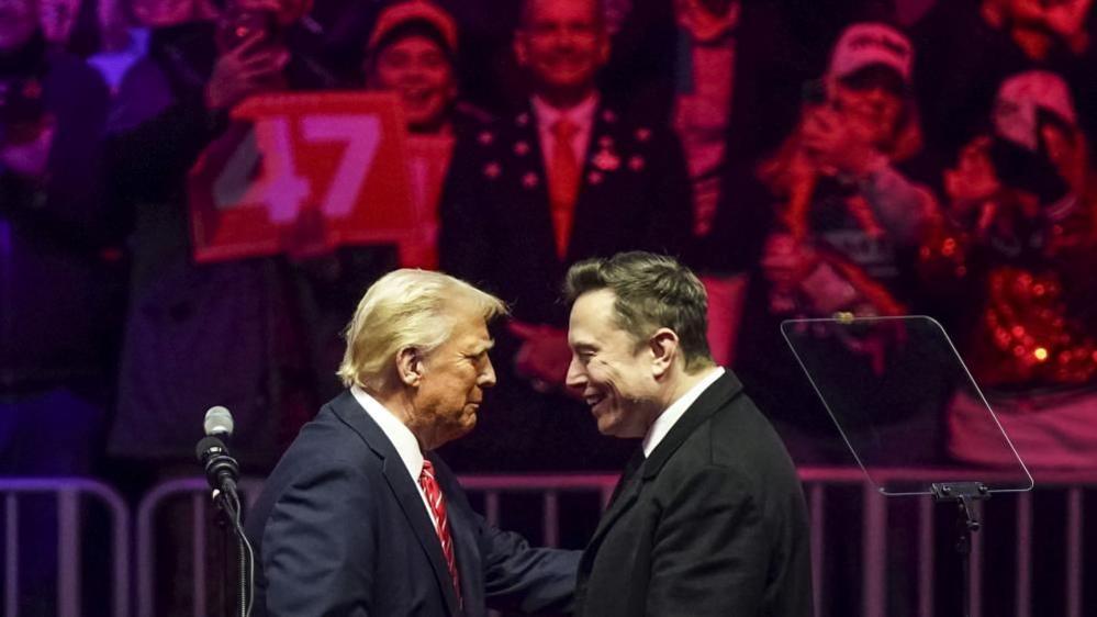 US President Donald Trump (L) with businessman Elon Musk (R) on stage during a rally at Capital One Arena in Washington, DC on19 January 2025