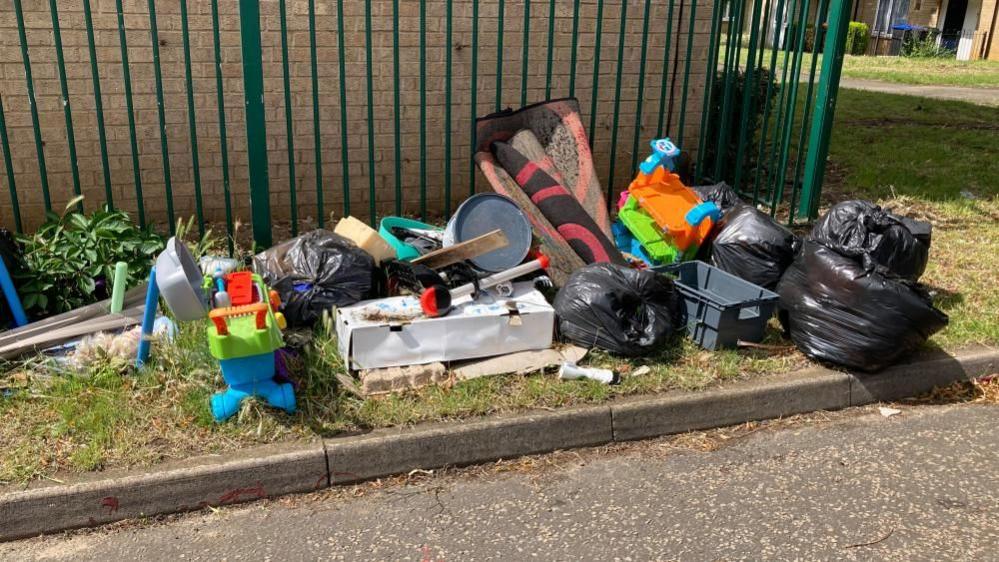 A pile of litter including old toys and gardening equipment