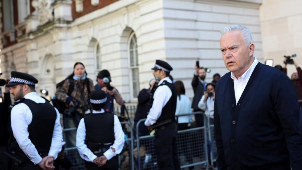 Photographers photograph Edwards from behind a barricade as he leaves court