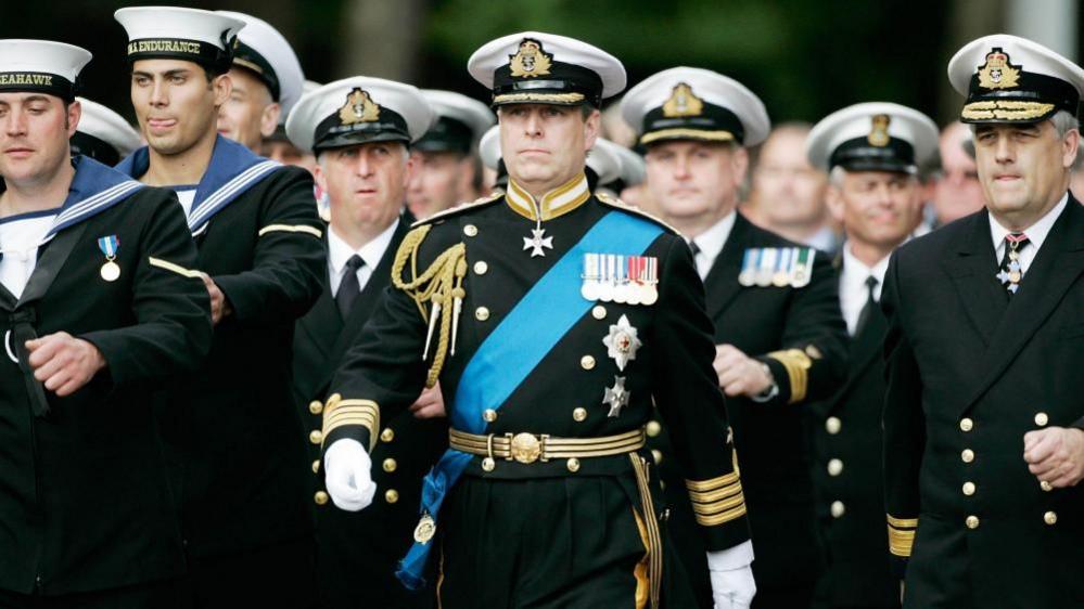 Andrew Mountbatten Windsor wearing a full military uniform marching alongside other Royal Navy personnel
