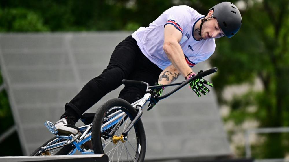 Jude Jones with black helmet and white top doing stunts on a BMX bike