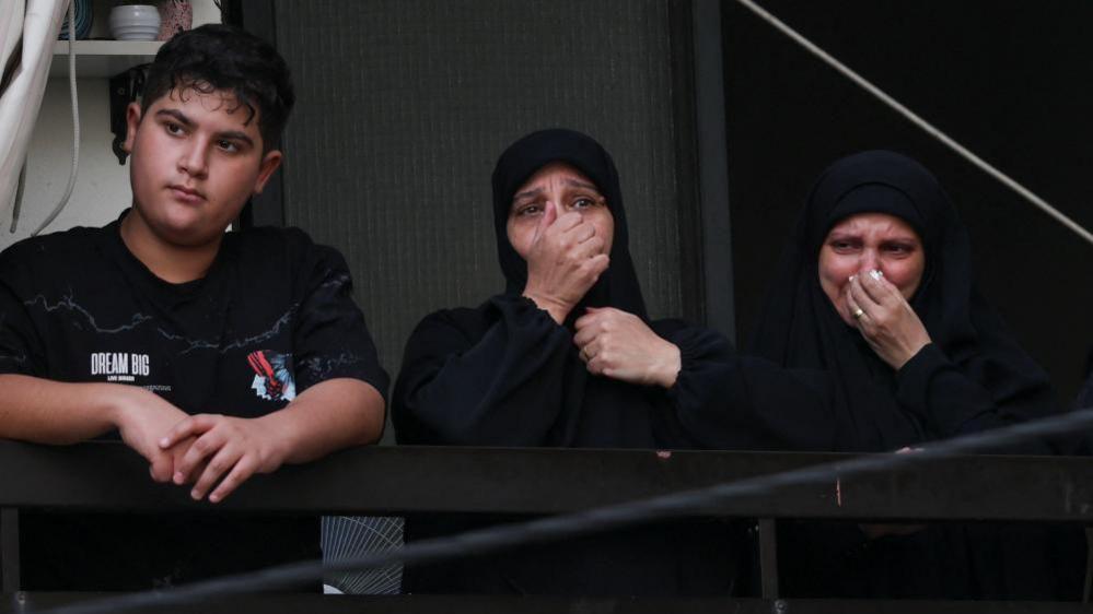 People mourn as they watch from a balcony during the funeral in Beirut, 18 Sept