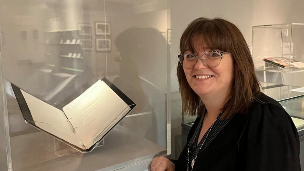 Natalie Fairweather wearing a black top, pictured near the collection of rejection letters sent to Malorie Blackman by publishers.