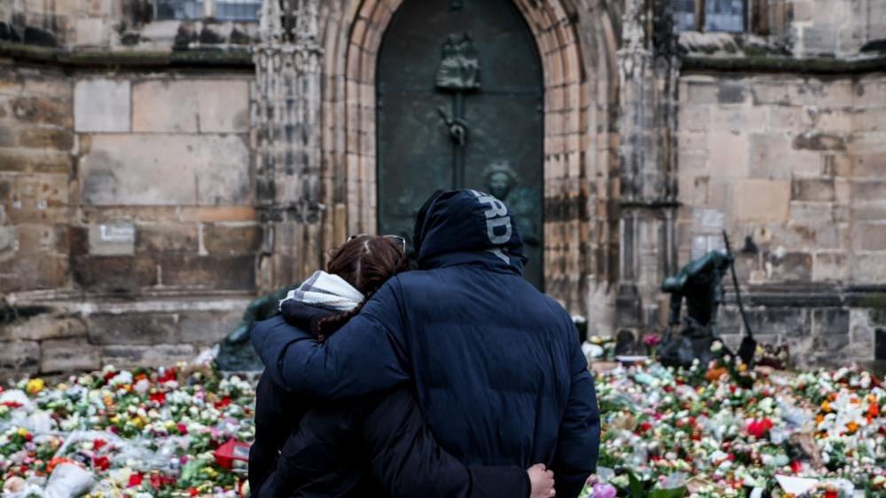 Two people mourn in front of St. John's Church in Magdeburg