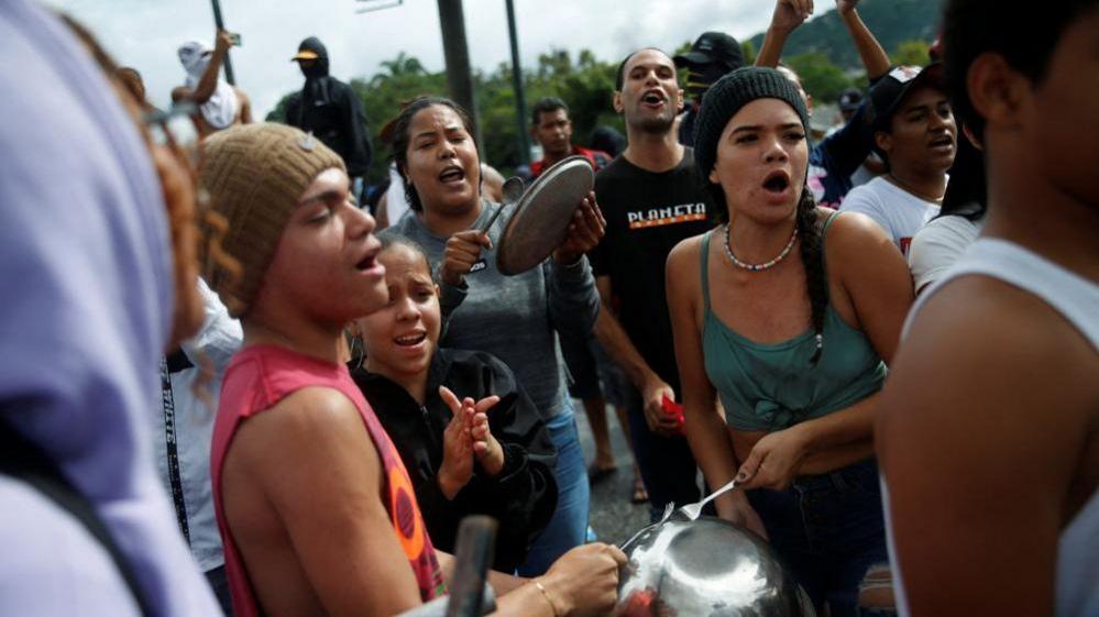 people protest by banging pots in Caracas