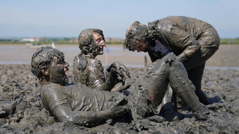 Competitors take part in the annual Maldon Mud Race, a charity event to race across the bed of the River Blackwater in Maldon, Essex