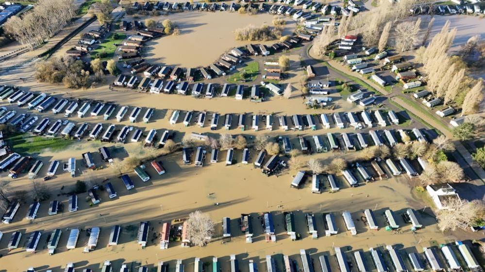 A drone shot of the caravan park showing dozens of caravans lined up submerged in brown water.