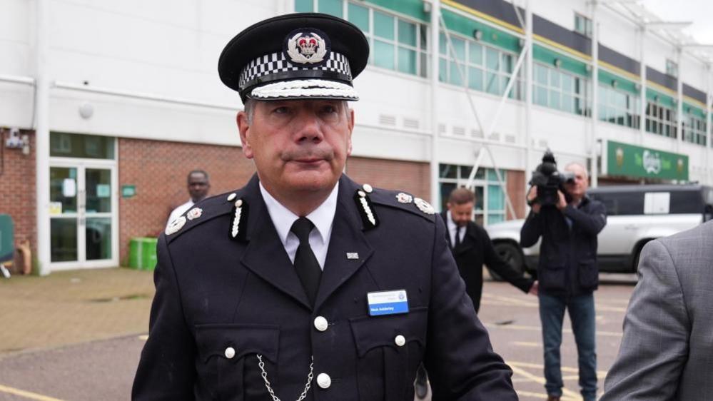 Nick Adderley wearing police uniform walking in a car park