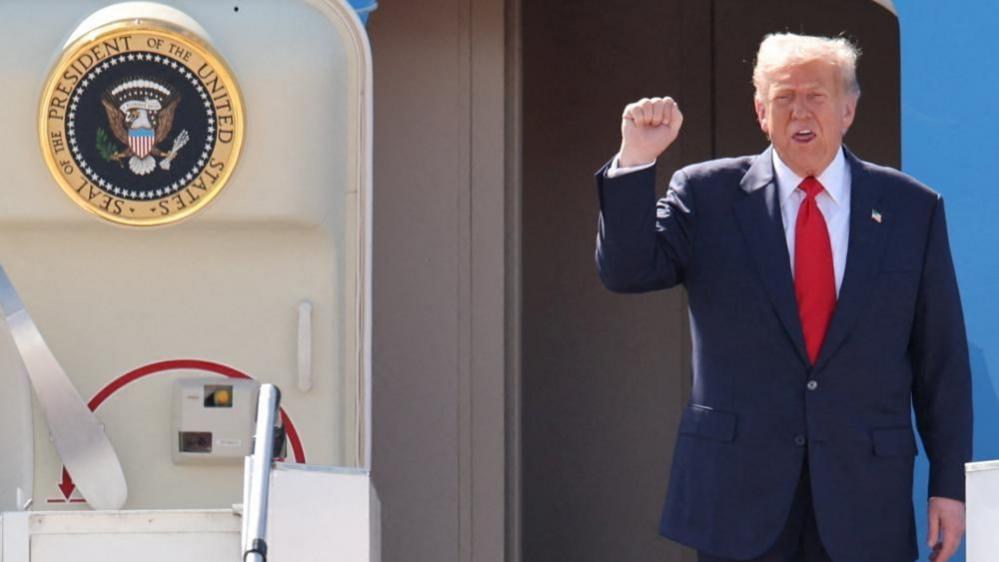Donald Trump raises his right fist as he exits Air Force One in Kuala Lumpur