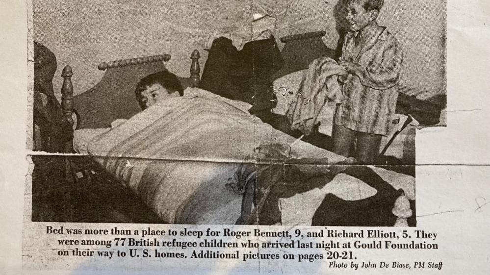 Newspaper cutting showing photograph of boy lying in bed, and a second boy in pygamas standing nearby, plus caption. The cutting says the photograph was taken by John De Biase