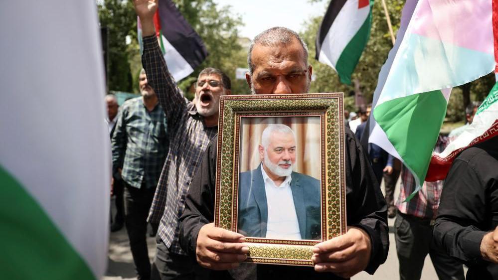 A man carrying a picture of Ismail Haniyeh