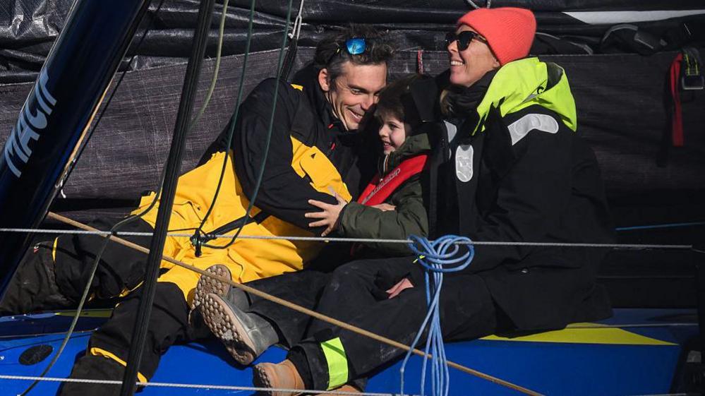 Charlie Dalin embraces his partner and their child on his boat after winning the 10th edition of the Vendee Globe in 2025