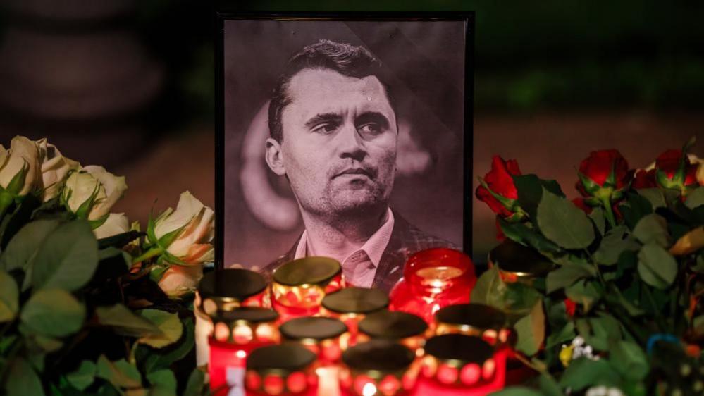Candles stand in front of a photo of the deceased US political activist Charlie Kirk during a vigil