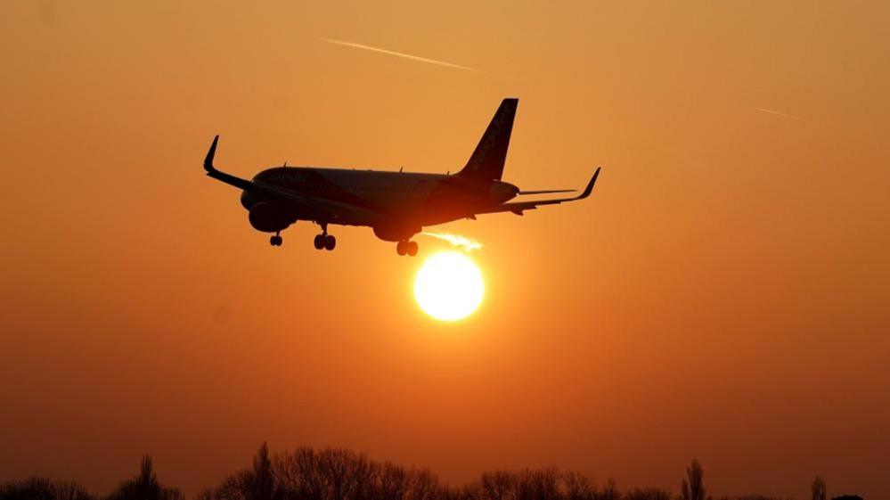 A plane flying into the sunset.