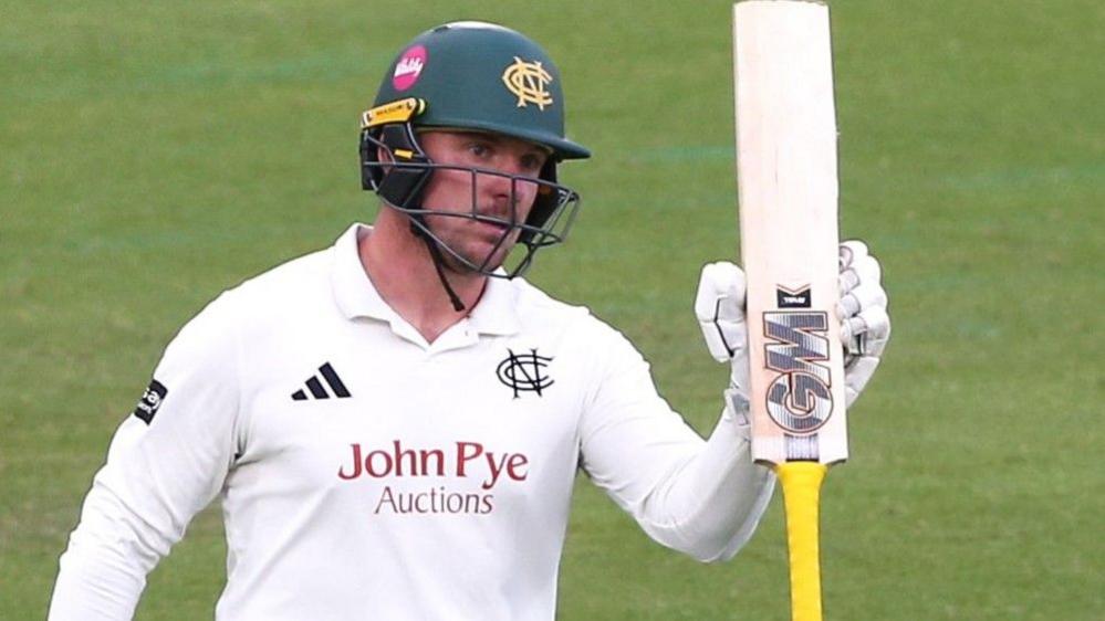 Liam Patterson-White raises his bat after reaching a half-century
