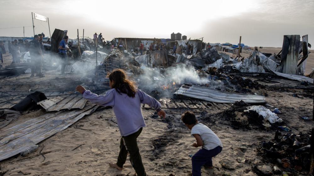 Palestinians inspect the damage after an Israeli army raid on a camp at an area designated for displaced people in Rafah, southern Gaza Strip.