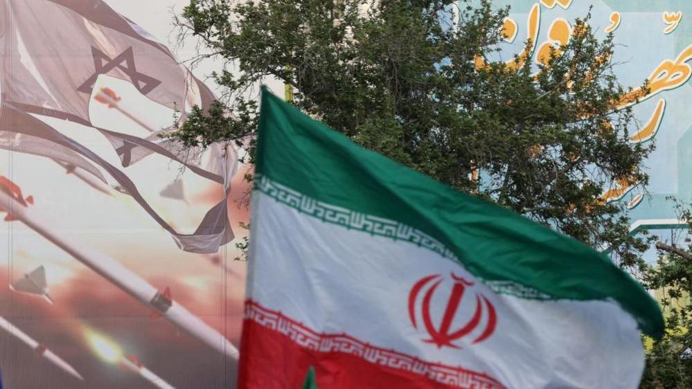 FILE PHOTO: An anti-Israel billboard is seen next to the Iranian flag during a celebration following the IRGC attack on Israel, in Tehran, Iran, April 15, 2024.