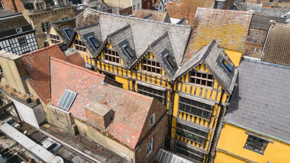 An aerial photo showing 26 Westgate Street, Gloucester, a yellow building with 16th century facade