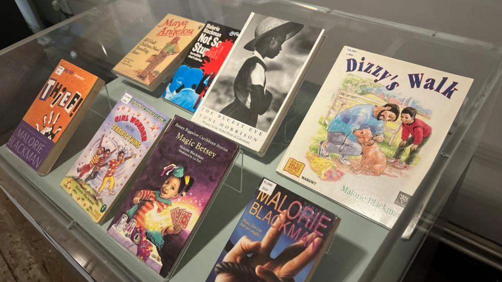 A selection of Malorie Blackman's books in a display case, on a perspex stand