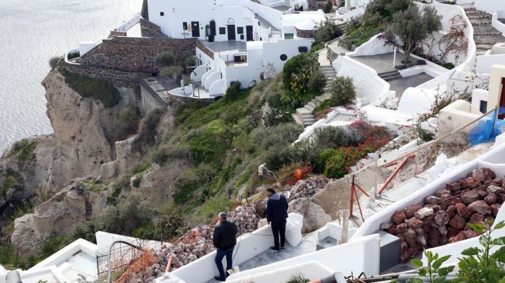 People examine their property in the almost evacuated village of Oia on Santorini island, Greece, 05 February 2025