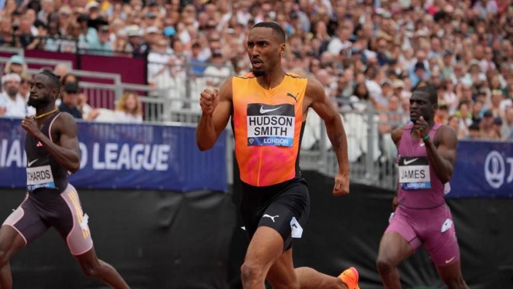 Matthew Hudson-Smith wearing an orange vest runs on a London track