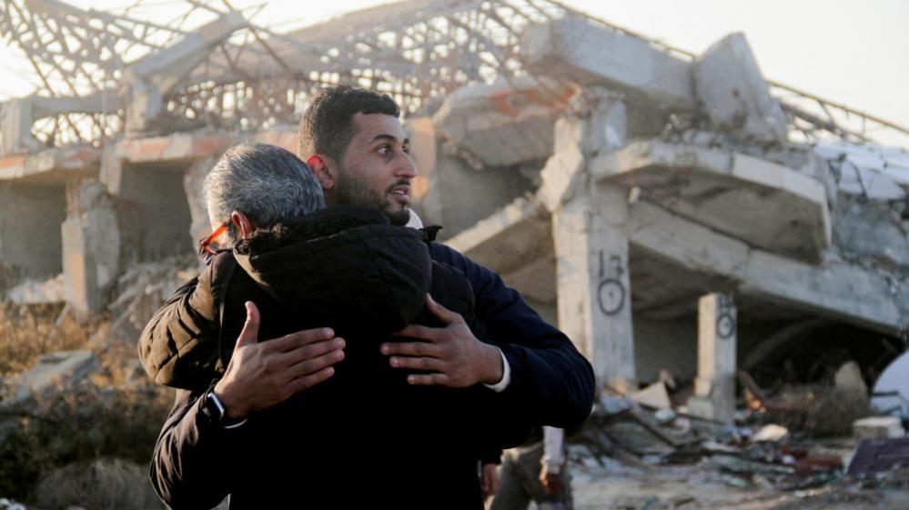 Palestinians returning to their homes hug in front of the remains of a building in Gaza City (27/01/25)