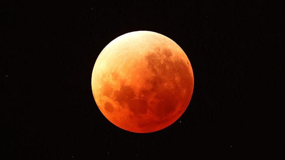 Close up picture of the Moon which has turned a rusty red colour during a full lunar eclipse