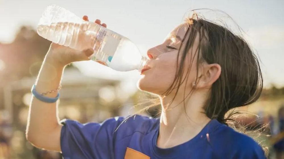 girl in blue tshirt drinking a water bottle