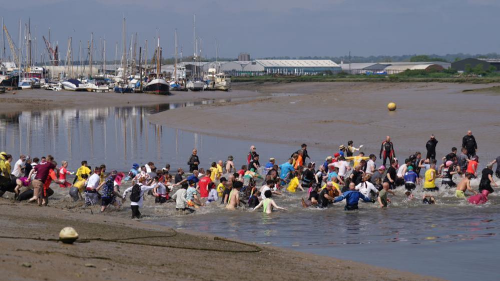 Competitors take part in the annual Maldon Mud Race, a charity event to race across the bed of the River Blackwater in Maldon, Essex