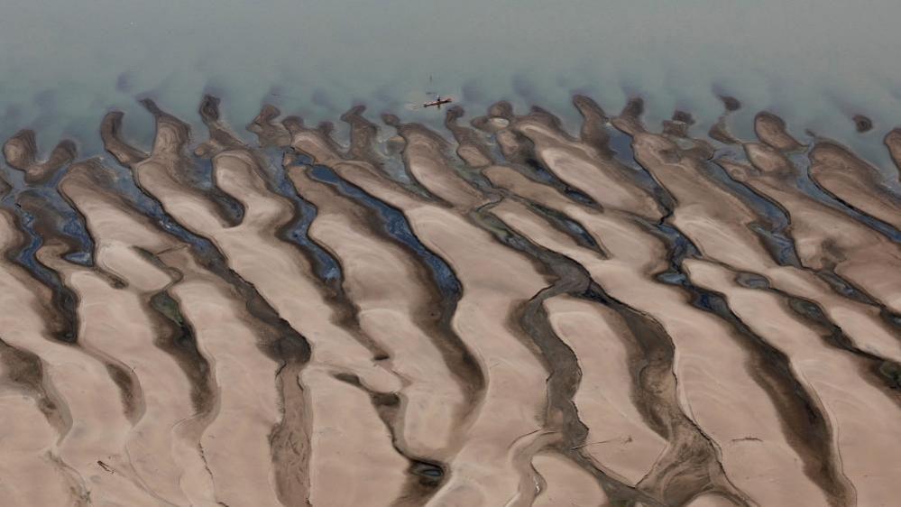 A man rides a boat in front of the sandbanks at the Solimões  River, one of the largest tributaries of the Amazon River, near Tefe, Amazonas state, Brazil September 17, 2024