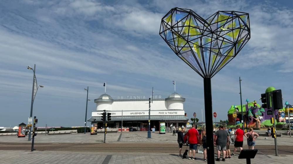 A heart, made of steel tubes in a geometric shape, aloft a pole. It is mounted in view of the Britannia Pier.