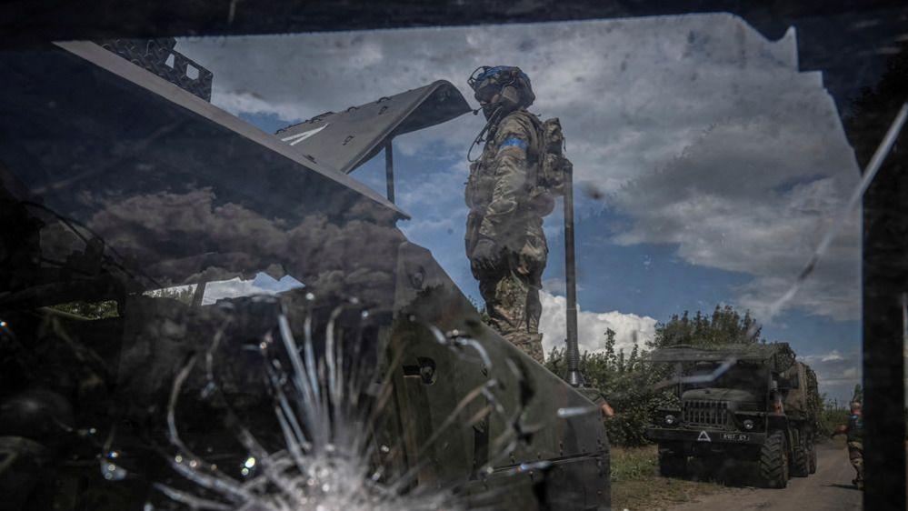 A Ukrainian soldier stands next to a broken military vehicle, in Sumy region, Ukraine August 11, 2024