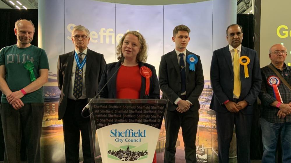 Olivia Blake celebrates at the lectern