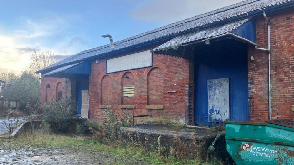 An old looking dark brick building with blue doors and a blue roof