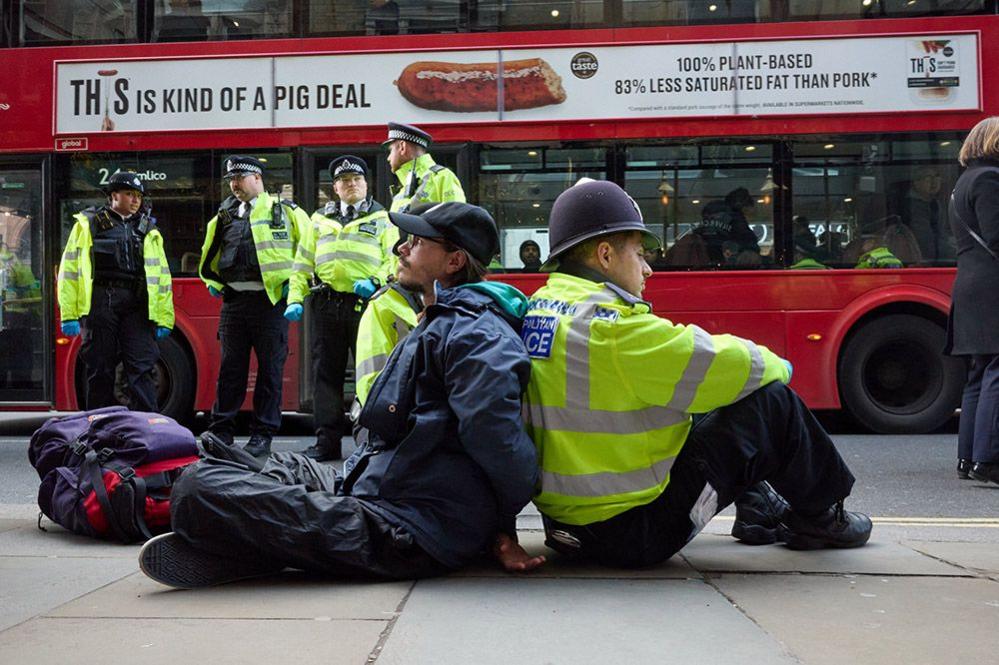 A man sits back-to-back with a police officer