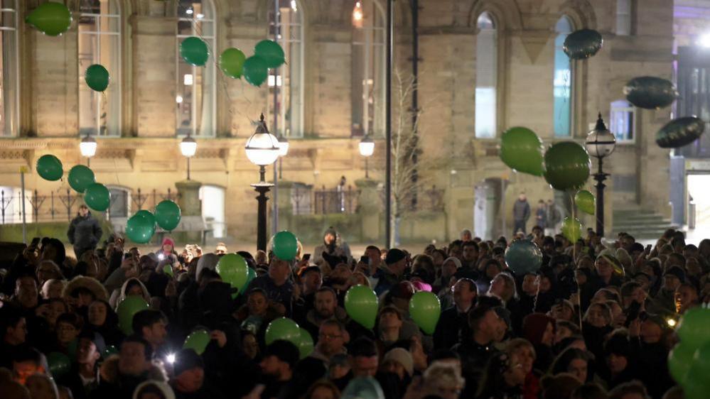 Image shows people holding green balloons during a vigil for James Lee Williams, popularly known as The Vivienne, in Liverpool on 12 January, 2025
