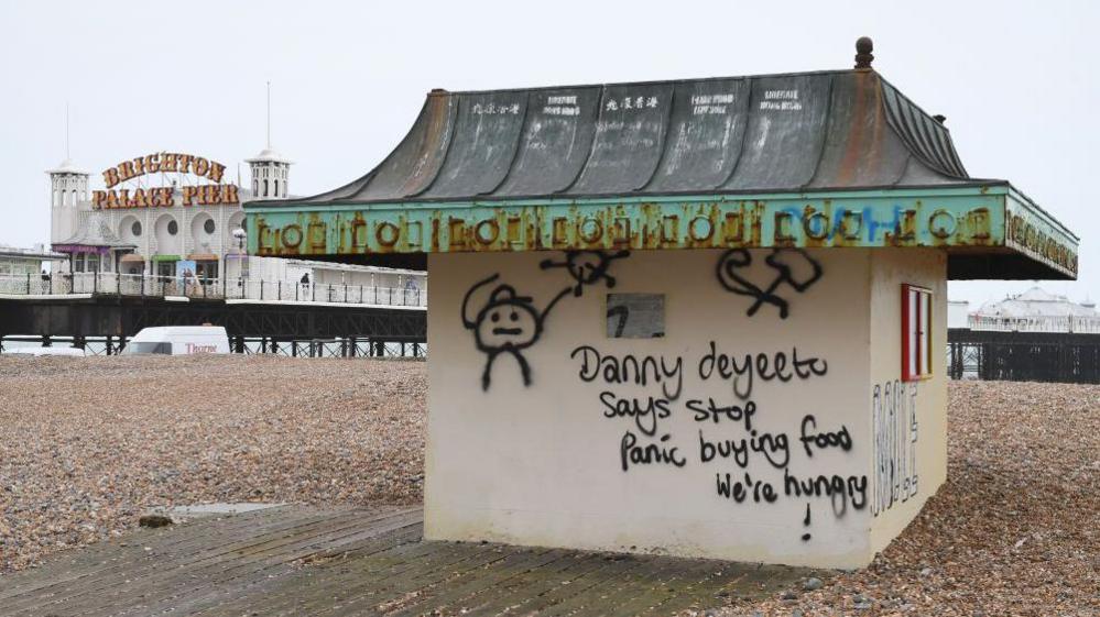 Graffiti on a hut on Brighton beach with the pier in the background