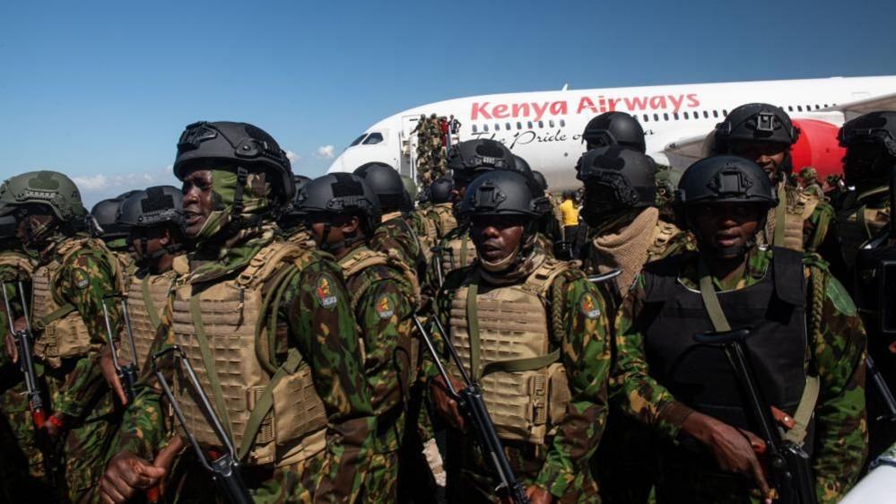 Armed police officers wear protective vests as they line up in front of a 'Kenya Airways' plane 