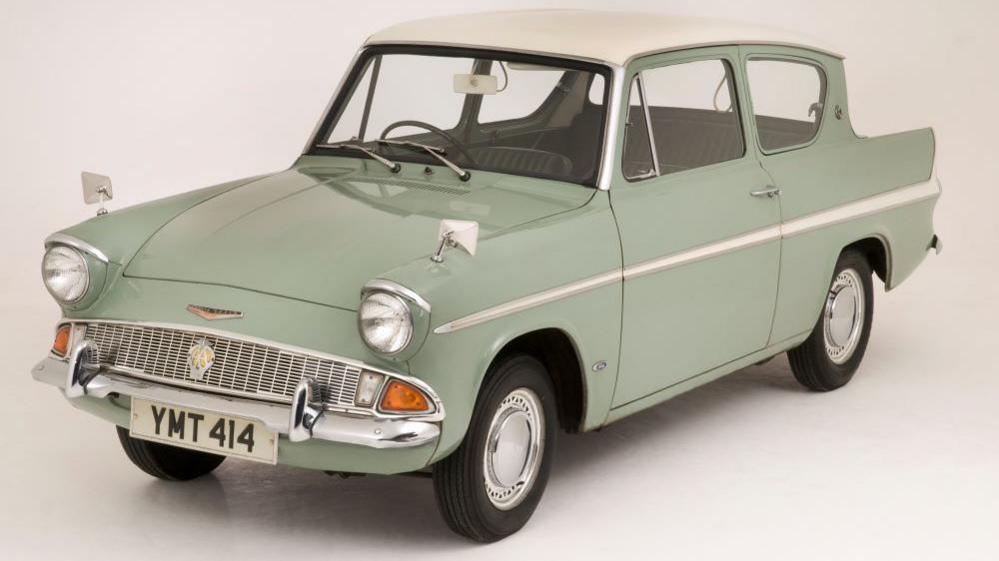 A sage green vintage car in a white studio. 
