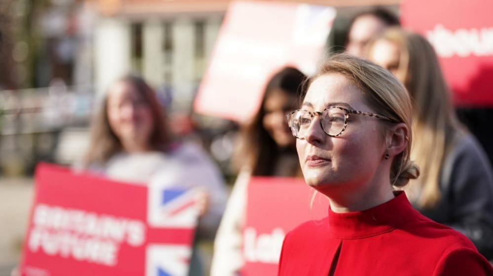 Gen Kitchen with supporters and wearing glasses in red top