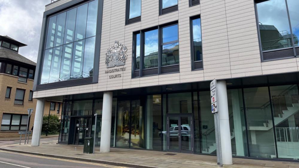 Chelmsford Magistrates Court is a three storey building, with glazed walls and pillars supporting the upper storeys. Panels of masonry clad the walls with large windows on the upper floors. The royal warrant and the words "Magistrates Court" appear on the building. 