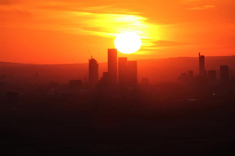 A beautiful, orange sunset that shows the sun setting behind towers