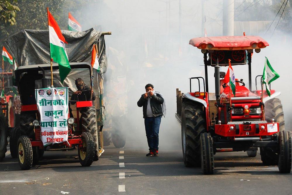 A farmer covers his face to protect himself from tear gas