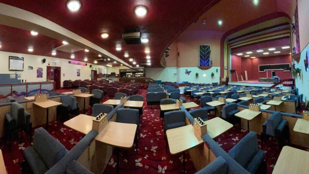 A panoramic fish-eye style photo of the venue with bingo seats and tables underneath the circle in an Art Deco theatre